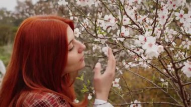 Kızıl saçlı kız bahar çiçeği kokusu alıyor. Bahar havası.