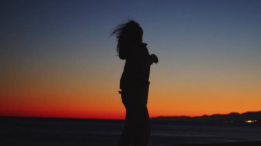 Gün batımında dans eden bir kızın silueti.