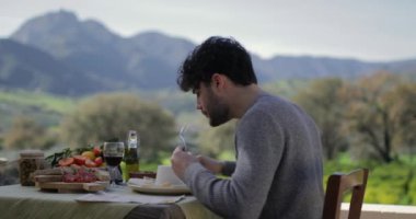 Dışarıdaki lokanta masasında oturan adam.