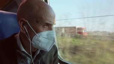 Yaşlı adam trenin camından dışarı bakıyor.