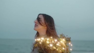 Kız elinde ışıklarla kumsala koşuyor.