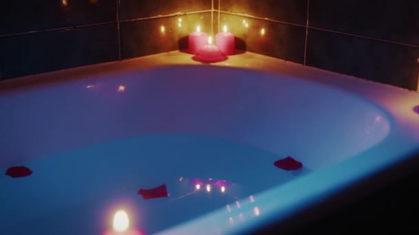 Wanna z romantycznymi świecami zapachowymi i płatkami — Wideo stockowe