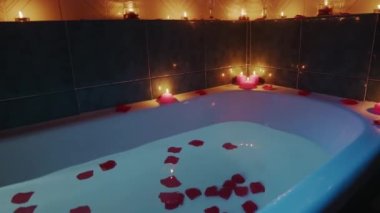 Romantik kokulu mumlar ve yapraklarla dolu bir küvet.