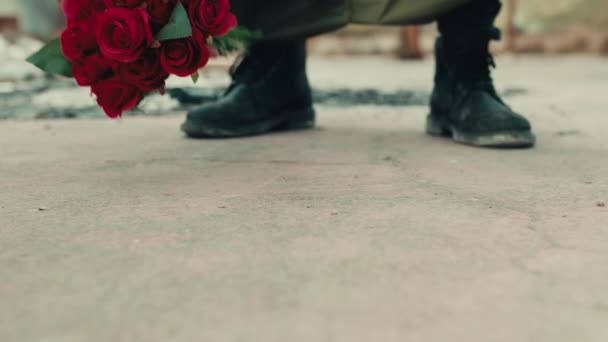 Ember támaszkodik csomó vörös virágok a földön — Stock videók