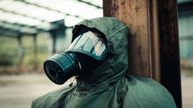 Soldier with gas mask is resting on the ground
