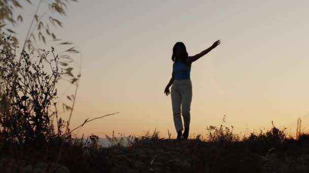Κορίτσι περπατά με ανοιχτές αγκάλες στο ηλιοβασίλεμα — Αρχείο Βίντεο