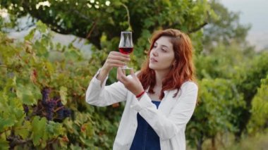 Girl in white coat checks the quality of grapes in the vineyard