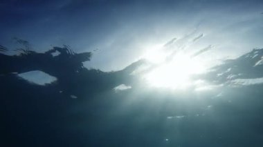 Moonlight beams shining from above through deep clear blue water 