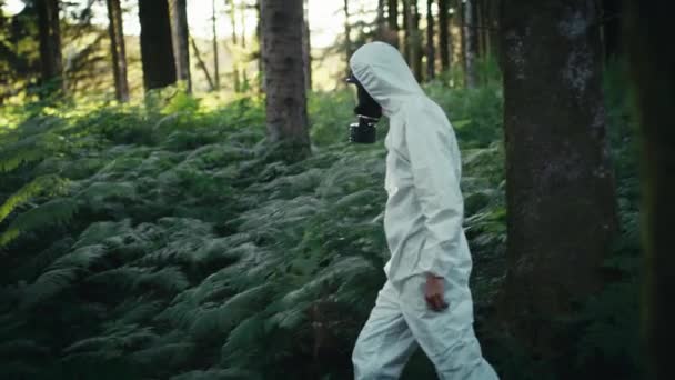 Άνθρωπος Μολυσμένη Άσπρη Στολή Και Μάσκα Αερίων Περπατάει Στα Βουνά — Αρχείο Βίντεο