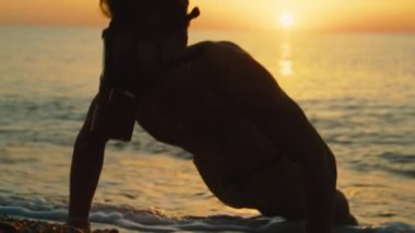 Adam gün doğumunda gaz maskesiyle sahilde antrenman yapıyor.