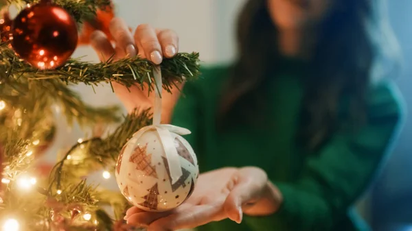 Hand Hangs Balls On Christmas Tree.