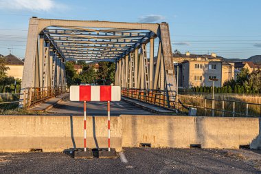Damaged bridge, closed with concrete barriers and traffic sign.