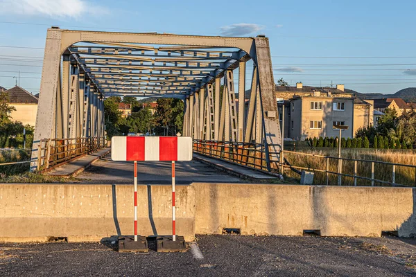 Damaged bridge, closed with concrete barriers and traffic sign.