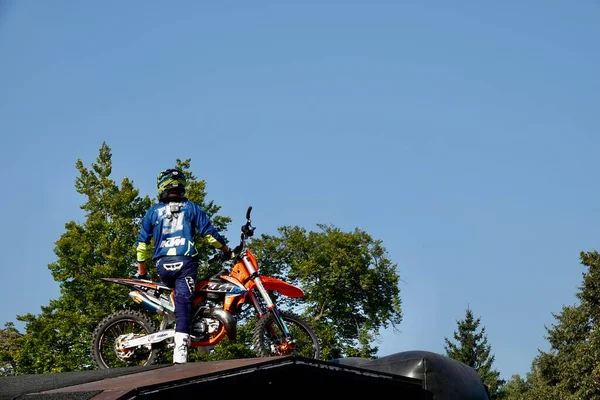 Prag, Tschechien - 4. September 2021: Motocross-Fahrer im blauen Overall mit Helm sitzt auf seinem Motorrad an der Spitze der Sprungschanze. — Stockfoto