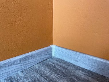 Ahşap desenli plastik süpürgelikli halı. Yeni yapılmış ahşap halılar döşeme ve süpürgelikler evde. Modern tasarım. Plastik kaplamalar ve karamel duvarlar. Yüksek kalite fotoğraf