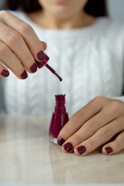 Tanınmayan genç bir kadın bir elinde oje şişesi, diğer elinde fırça tutarken şişenin içine damlıyor..