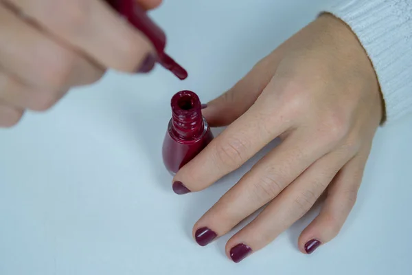 Bir elinde oje, diğer elinde de manikürlü oje fırçası var. Yukarıdan çekilmiş..