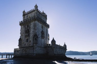 Güneşli bir günde Lizbon 'daki Tagus Nehri' nin kıyısındaki Belem Kulesi 'nin arkasında bir yelkenli var.