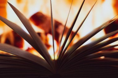 Şöminenin arka planında yanan bir kitabın sayfaları ikiye bölünmüş..