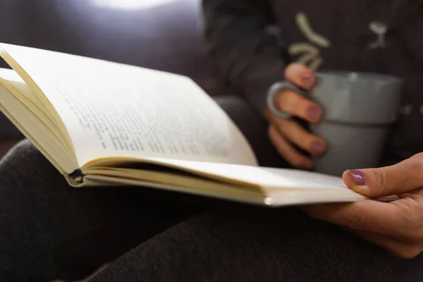 Kitap okurken ve elinde bardak tutarken tanınmayacak halde olan bir kız..