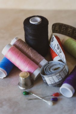 Çeşitli renklerde iğne, yüksük ve mezura ile iplik makaraları kümesi