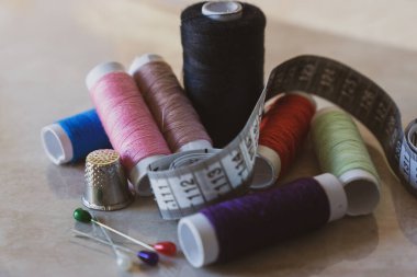 Çeşitli renklerde iğne, yüksük ve mezura ile iplik makaraları kümesi