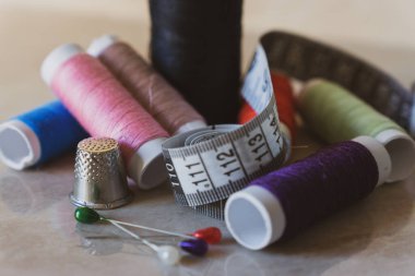 Çeşitli renklerde iğne, yüksük ve mezura ile iplik makaraları kümesi