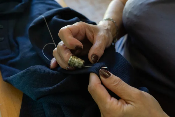 目に見えない女性の手が糸とシンブルで衣服を縫う — ストック写真