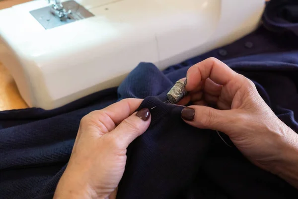 目に見えない女性の手が糸とシンブルで衣服を縫う — ストック写真