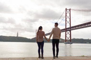 Çift el ele tutuşup 25 Nisan köprüsüne ve Tagus nehrine bakıyor..