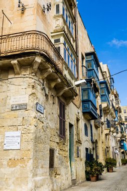Açık bir günde balkonları ve mavi pencereleri olan tipik Malta caddesi.