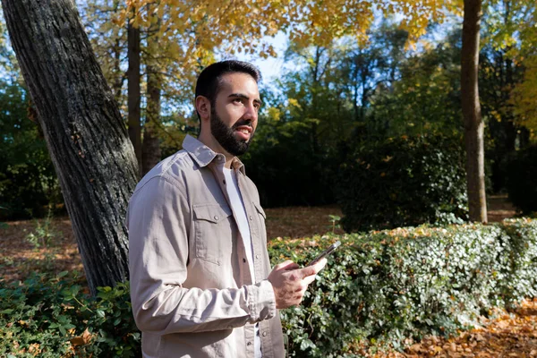 Bir sonbahar günü sokakta akıllı telefonlu genç bir adam..