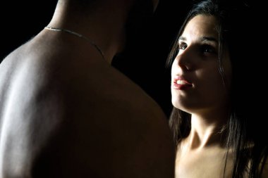 Portrait of a very sensual young couple with marked lights and shadows while looking into each other's eyes.