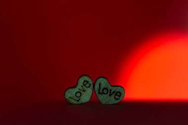 Wooden hearts in the foreground of valentine's day decoration with illuminated red background.