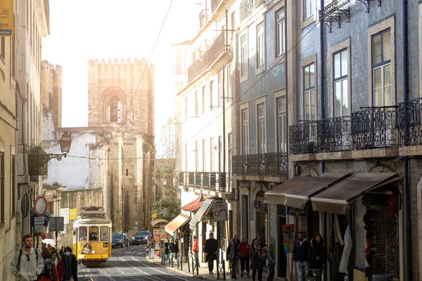 Lizbon Caddesi 'nde insanlar yürüyor, tipik sarı tramvay kalkıyor ve arka planda Lisbon Katedrali var..