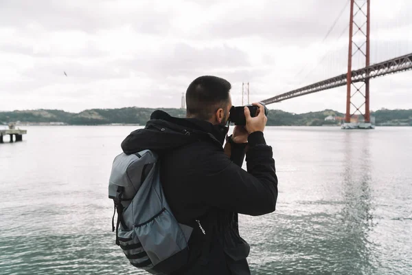 Genç fotoğrafçı, bulutlu bir kış gününde Lizbon 'daki ünlü 25 Nisan Köprüsü' nün fotoğrafını çekiyor..