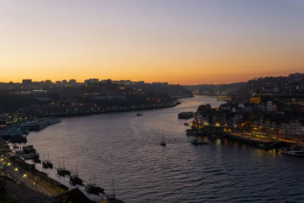 Gün batımında Douro Nehri 'nin manzarası. Tekneler yelken açıyor ve sokak lambaları yanıyor..