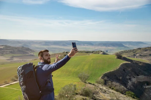 Genç sakallı adam akıllı telefonuyla selfie çekiyor. Seyahat ve teknoloji konsepti.