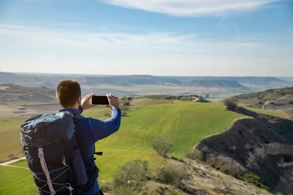 Sırt çantalı tanınmayan genç adam akıllı telefonuyla fotoğraf çekiyor. Teknoloji ve seyahat kavramı.
