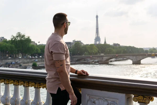 Young boy looking at the eiffel tower and the seine river from a bridge in paris