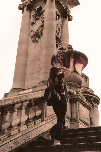 Unrecognizable young photographer taking a photo while walking up a staircase with a monument in the background