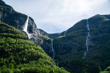 Large waterfall that rises in the mountains surrounded by green trees in Norway