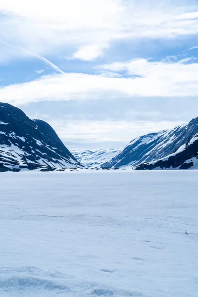 Landscape of a frozen lake with mountains in the background and lots of snow in Norway.