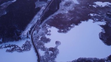 Road in winter forest aerial view with lakes