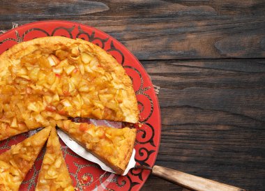 Eski ahşap desenli arka planda metal bir spatulada tarçınlı dilimlenmiş elmalı turta..