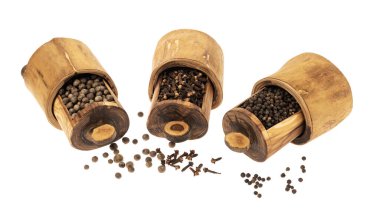 Karabiber tohumları ve karanfiller beyaz arka planda tahta bir fıçıda.