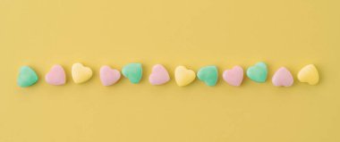 Parlak sarı arka planda çok renkli kalp hapları. Hastalar için verilen ilaçlar. Sağlık için ilaçlar ve vitaminler.