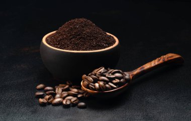 Kahve fincanının içinde koyu arkaplanda bir kaşık kahve çekirdeği.