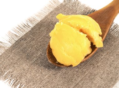 Çuval bezinde kaşık içinde ghee, beyaz arka plan. Saf ghee.