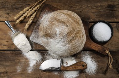 Kenevir unuyla tatlandırılmış taze ekşi ekmeğin yuvarlak bir somunu kesme tahtasının üzerinde bir bıçakla. Karanlık bir masada tohumlu ekmek. Ülke tarzı ekşi ekmek